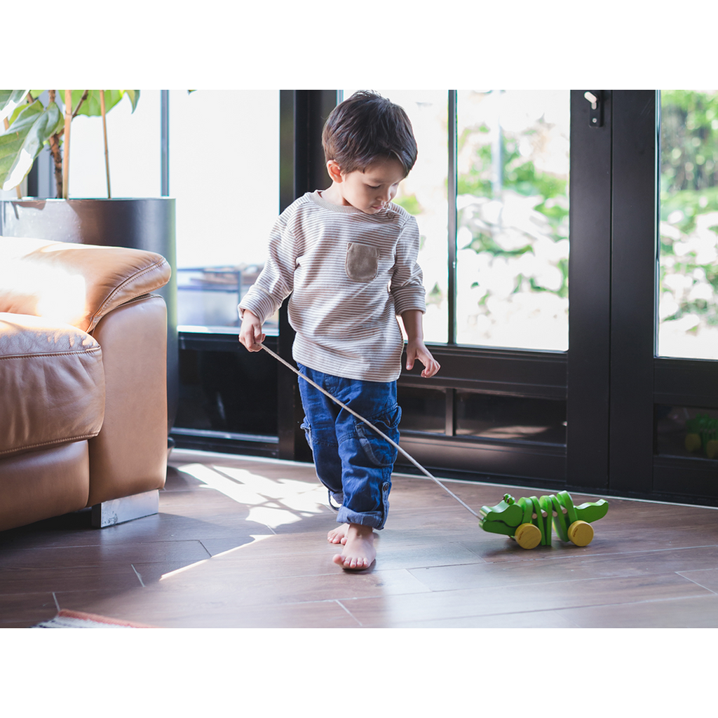 Kid playing PlanToys Dancing Alligator