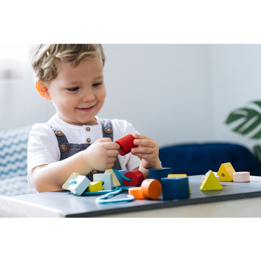 Kid playing PlanToys Geo Lacing Beads - Unit Plus