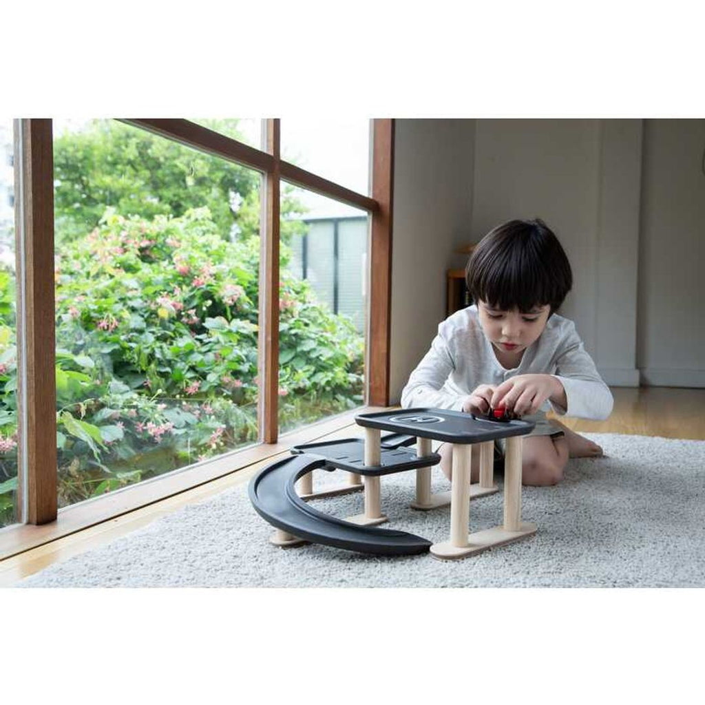 Kid playing PlanToys Race N Play Parking Garage