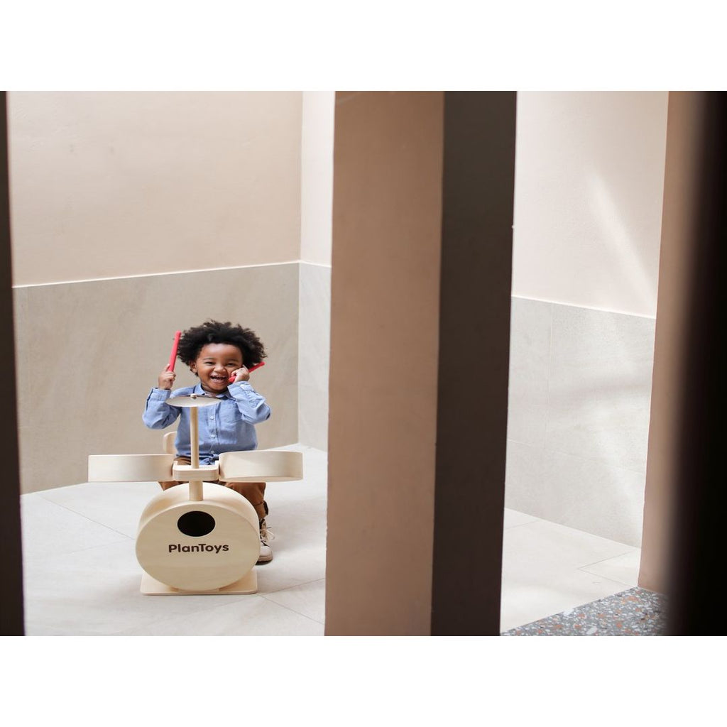 Kid playing PlanToys Drum Set